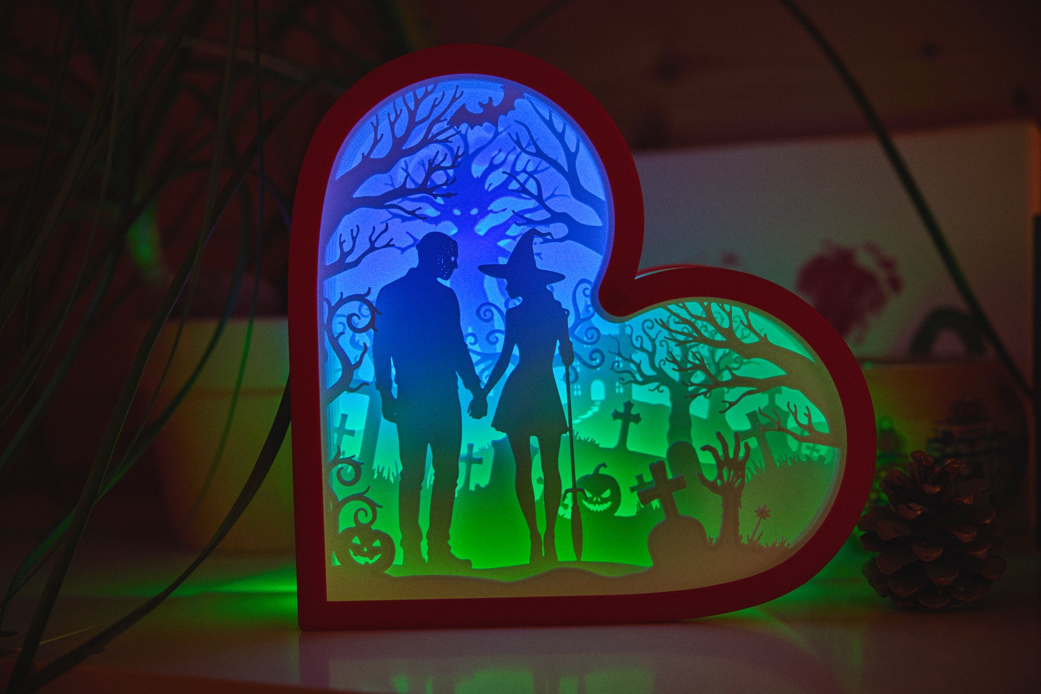 Heart-shaped light box with a silhouette of a couple in a graveyard scene, glowing in the dark.